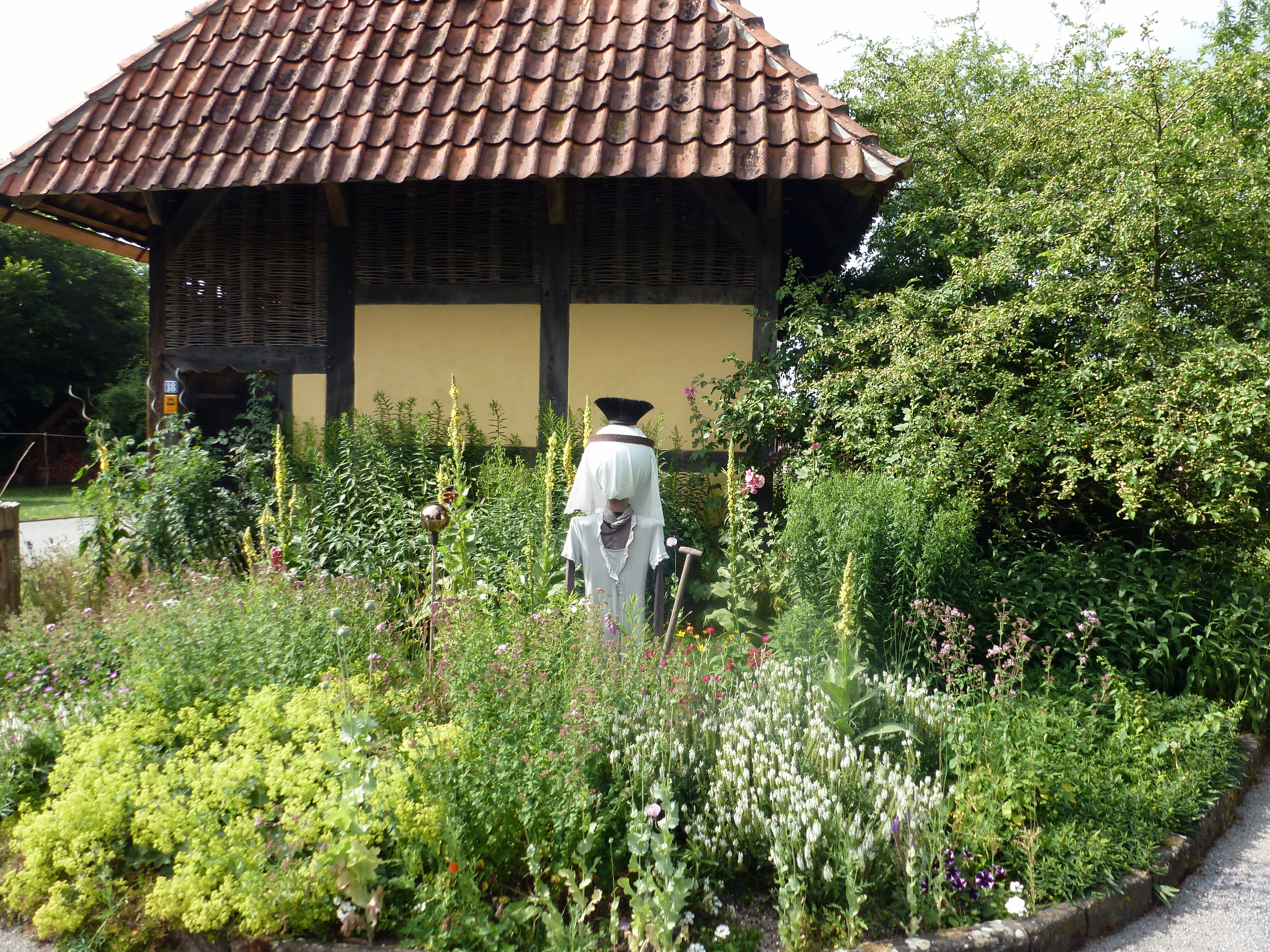 Vogelscheuche im Garten vor einem Fachwerkhaus