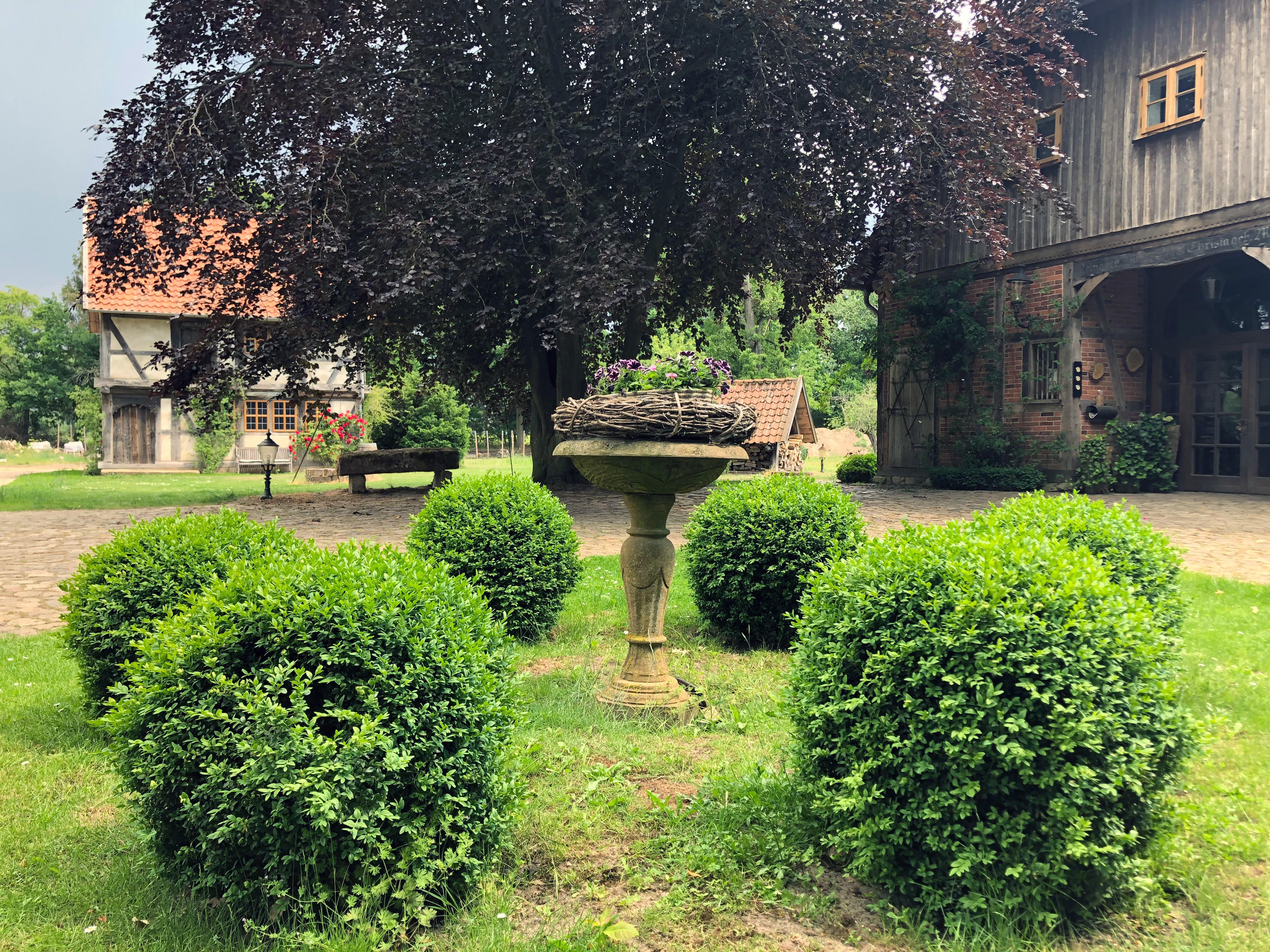 Sandsteinbrunnen mit Kranz darauf im Garten